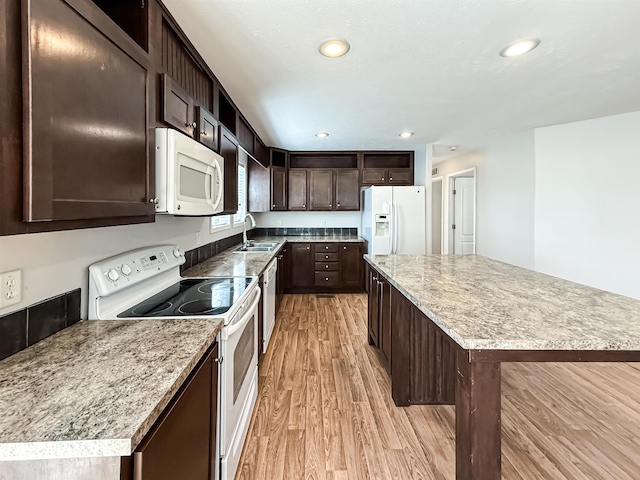 kitchen with light wood-style flooring, white appliances, recessed lighting, dark brown cabinetry, and a sink