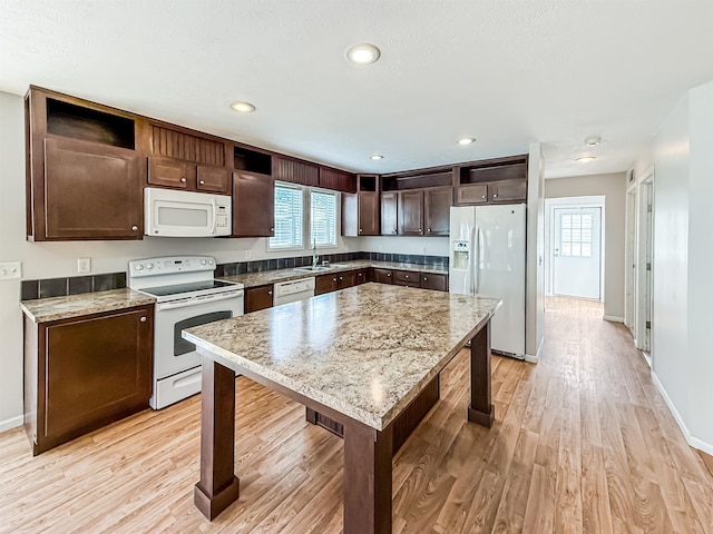 kitchen with dark brown cabinetry, light wood finished floors, recessed lighting, and white appliances