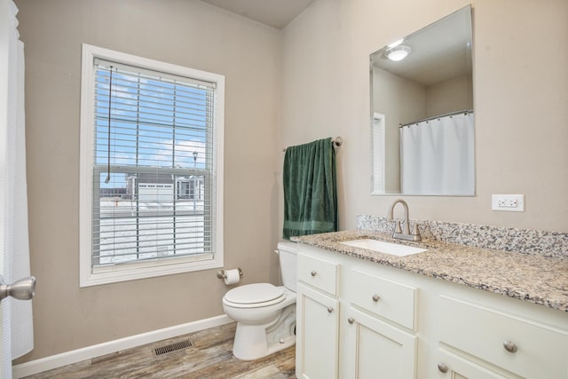 full bath with vanity, baseboards, toilet, visible vents, and wood finished floors