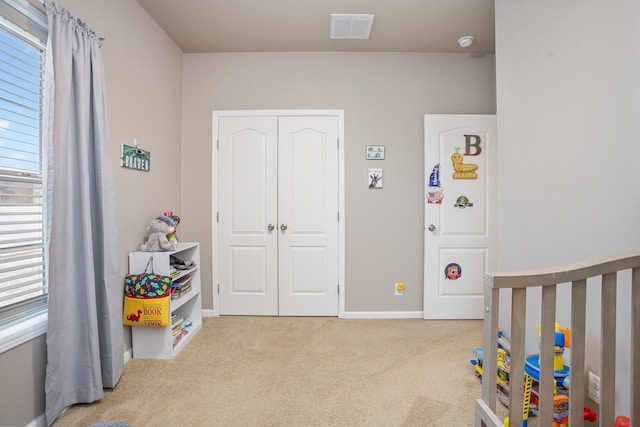 carpeted bedroom with a closet, visible vents, baseboards, and a nursery area