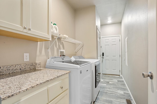 laundry room with light wood-style floors, visible vents, baseboards, cabinet space, and washer and clothes dryer