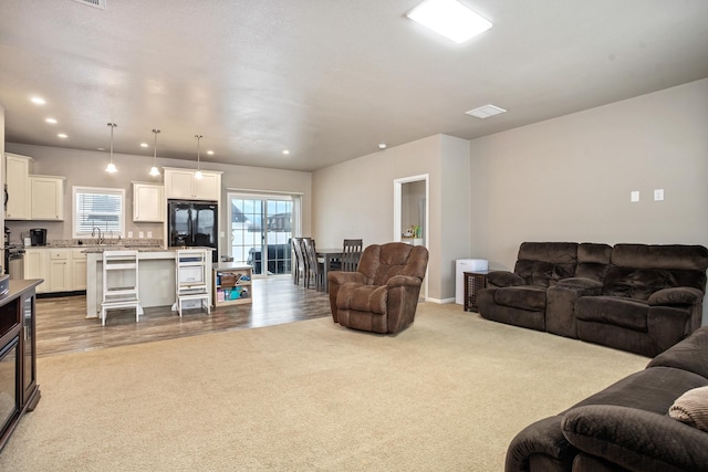 carpeted living room featuring a sink, visible vents, and recessed lighting