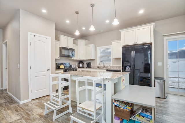 kitchen featuring a wealth of natural light, light wood-style flooring, white cabinets, black appliances, and a kitchen island