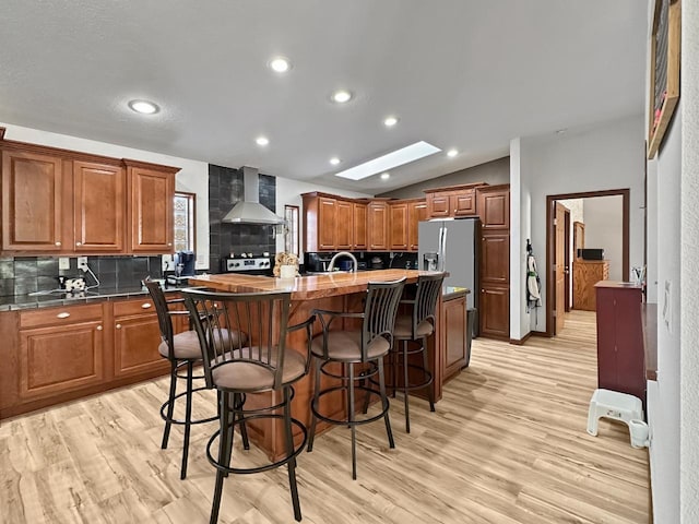 12780 153rd St, Sawyer, ND 58781 - kitchen featuring backsplash, light wood-style floors, a center island with sink, wall chimney exhaust hood, and lofted ceiling