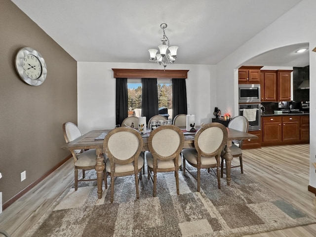 12780 153rd St, Sawyer, ND 58781 - dining room with baseboards, light wood-type flooring, arched walkways, and an inviting chandelier