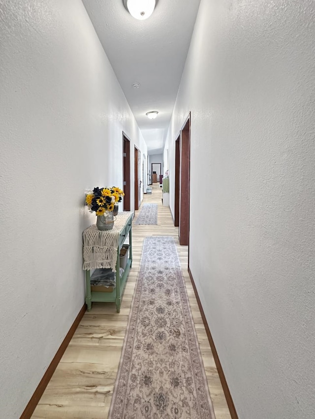 12780 153rd St, Sawyer, ND 58781 - hallway featuring light wood-type flooring, a textured wall, and baseboards