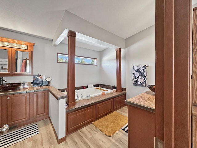 12780 153rd St, Sawyer, ND 58781 - full bath with visible vents, a bath, ornate columns, vanity, and wood finished floors
