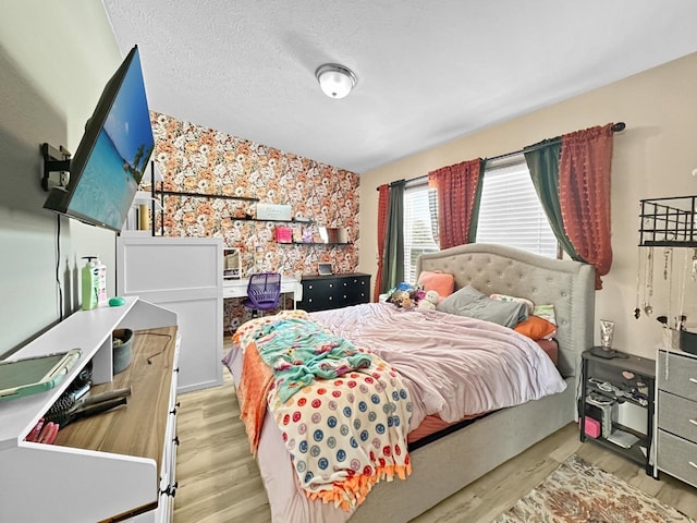 12780 153rd St, Sawyer, ND 58781 - bedroom with light wood finished floors, a textured ceiling, wallpapered walls, and an accent wall