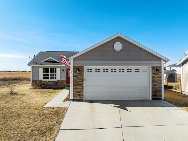 view of front of house with driveway, an outbuilding, a garage, and stone siding