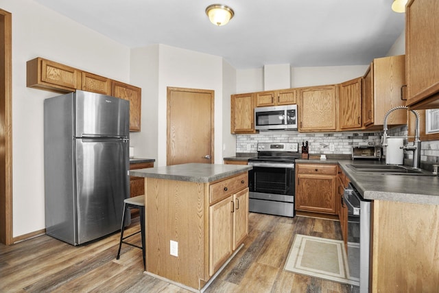kitchen featuring dark countertops, decorative backsplash, a sink, and appliances with stainless steel finishes