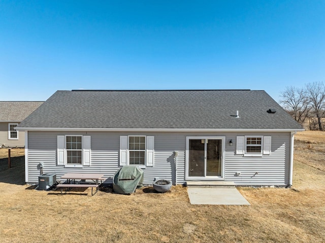 rear view of property featuring roof with shingles and a yard