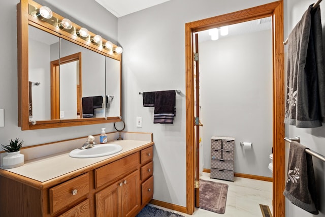 1419 17 1/2 Ave, Minot, ND 58701 - bathroom featuring visible vents, toilet, vanity, and baseboards