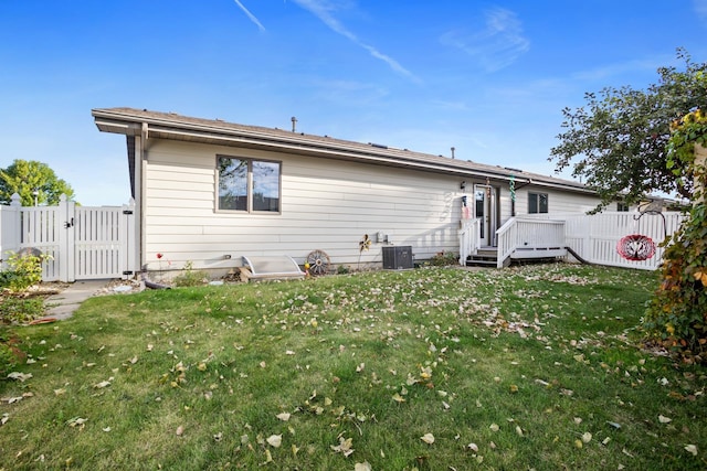 1419 17 1/2 Ave, Minot, ND 58701 - back of property with a lawn, central AC unit, fence, a gate, and a deck