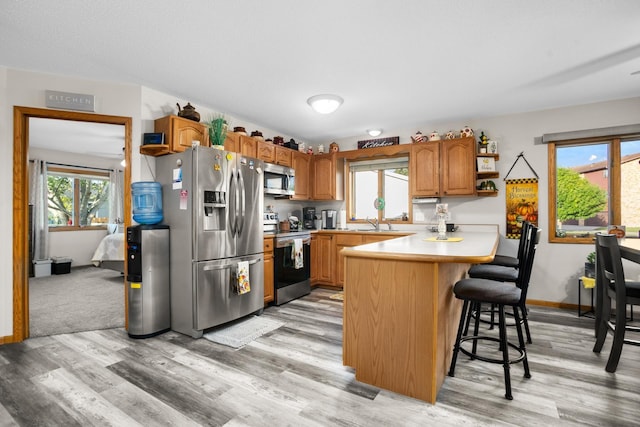 1419 17 1/2 Ave, Minot, ND 58701 - kitchen featuring a peninsula, light countertops, light wood-style floors, a kitchen bar, and appliances with stainless steel finishes