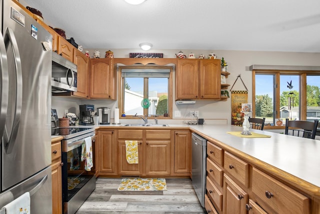 1419 17 1/2 Ave, Minot, ND 58701 - kitchen with brown cabinetry, light wood-type flooring, appliances with stainless steel finishes, light countertops, and a sink