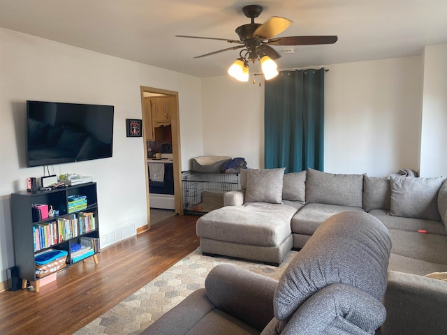 living room featuring visible vents, baseboards, wood finished floors, and ceiling fan