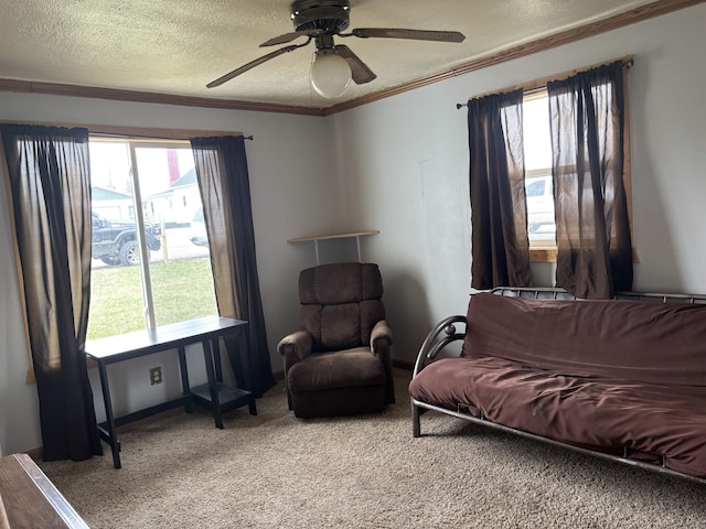 carpeted living room featuring a textured ceiling, a healthy amount of sunlight, a ceiling fan, and ornamental molding