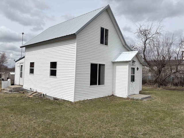 view of side of property featuring a lawn and metal roof