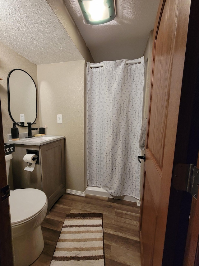 1425 9th St, Minot, ND 58701 - bathroom featuring wood finished floors, toilet, vanity, baseboards, and a textured ceiling
