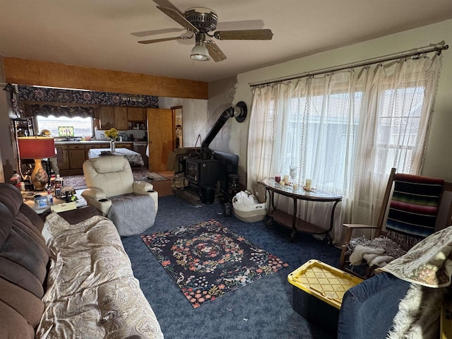 carpeted living room with ceiling fan and a wood stove