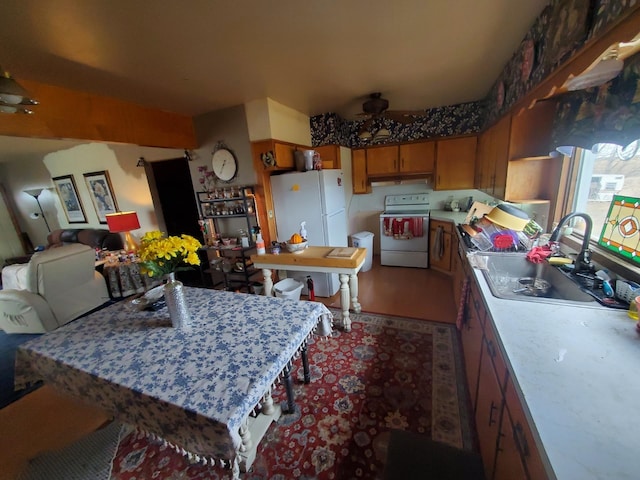 kitchen with a sink, brown cabinets, open floor plan, white appliances, and light countertops