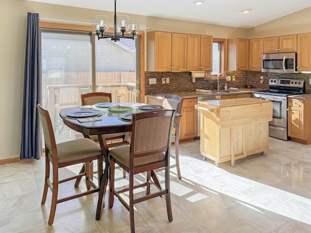 812 15 1/2 Ave SE, Minot, ND 58701 - kitchen with light brown cabinetry, a sink, tasteful backsplash, a chandelier, and appliances with stainless steel finishes