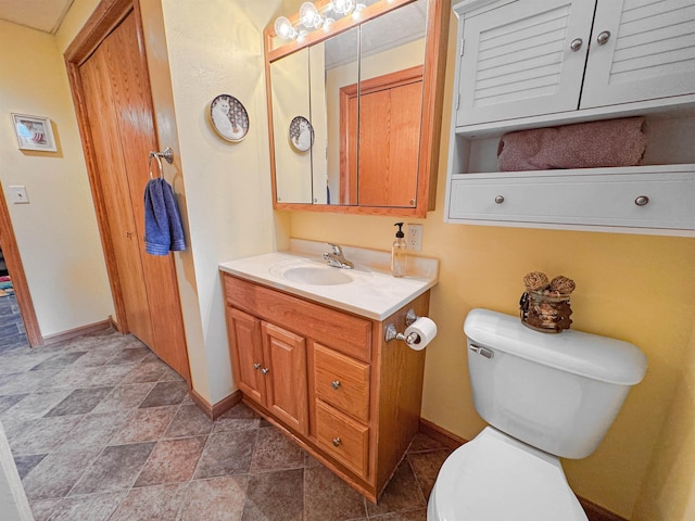 812 15 1/2 Ave SE, Minot, ND 58701 - bathroom with stone finish flooring, toilet, vanity, and baseboards