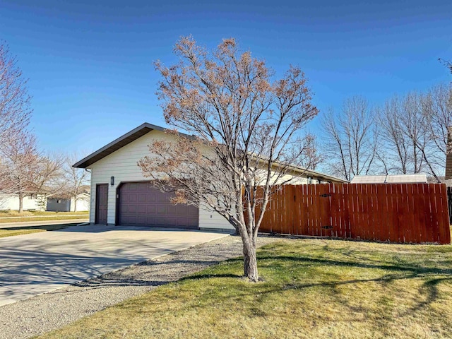 812 15 1/2 Ave SE, Minot, ND 58701 - view of side of home featuring fence, a lawn, driveway, and a garage
