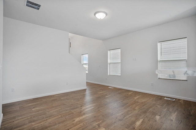 unfurnished room with wood finished floors, visible vents, and baseboards