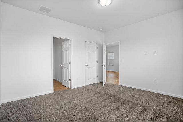unfurnished bedroom featuring visible vents, carpet, and baseboards