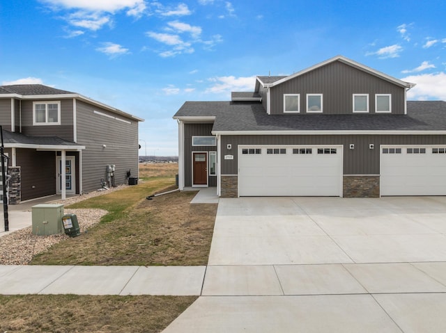 view of front of property with concrete driveway, board and batten siding, stone siding, a shingled roof, and an attached garage