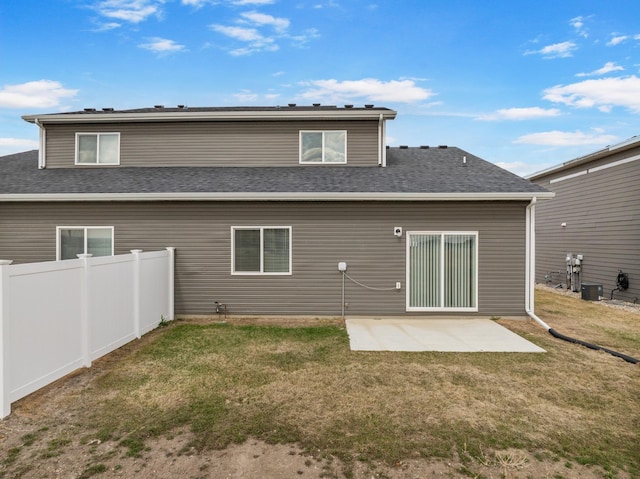 rear view of property featuring fence, a yard, central air condition unit, and a patio