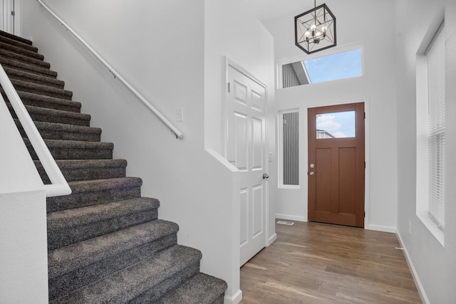 entryway with an inviting chandelier, stairway, wood finished floors, and baseboards