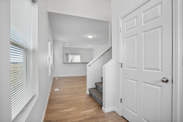 hall featuring baseboards, wood finished floors, and stairs