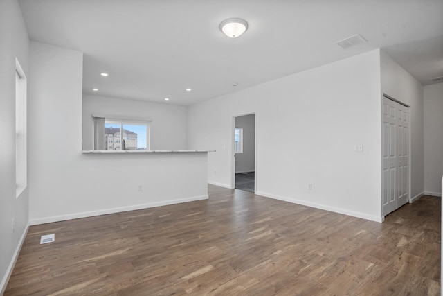 unfurnished living room with baseboards, visible vents, and wood finished floors