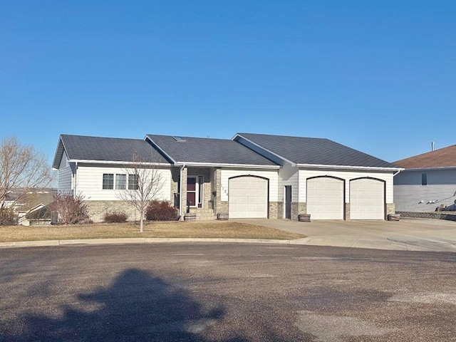 ranch-style home with stone siding, driveway, and an attached garage