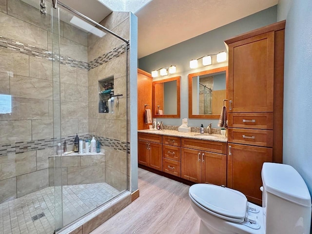 bathroom with wood finished floors, toilet, a stall shower, and a sink