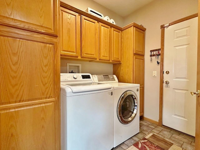 laundry area featuring cabinet space, baseboards, independent washer and dryer, and stone finish flooring