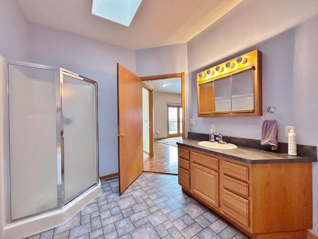 bathroom featuring a stall shower, a skylight, vanity, and stone finish flooring
