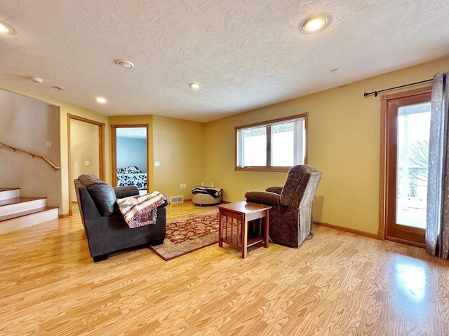 living room with stairway, recessed lighting, a textured ceiling, and light wood-style flooring