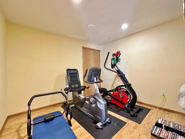 workout room with baseboards, recessed lighting, and wood finished floors