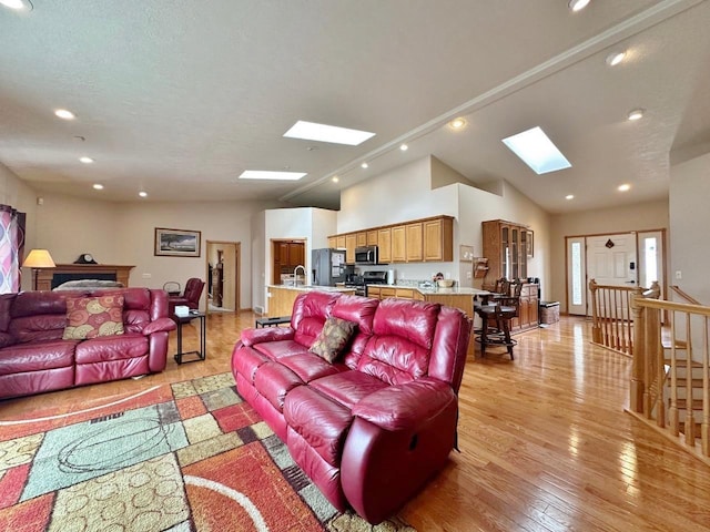 living area featuring recessed lighting, lofted ceiling with skylight, and light wood-style flooring