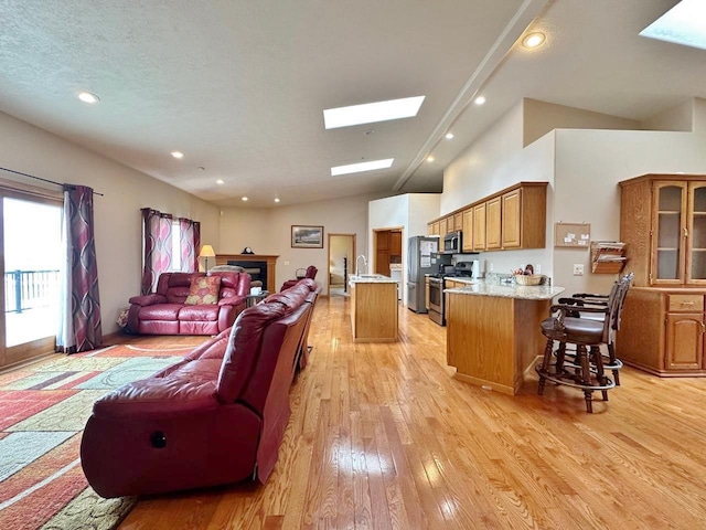 living room featuring light wood-type flooring, recessed lighting, high vaulted ceiling, and a skylight
