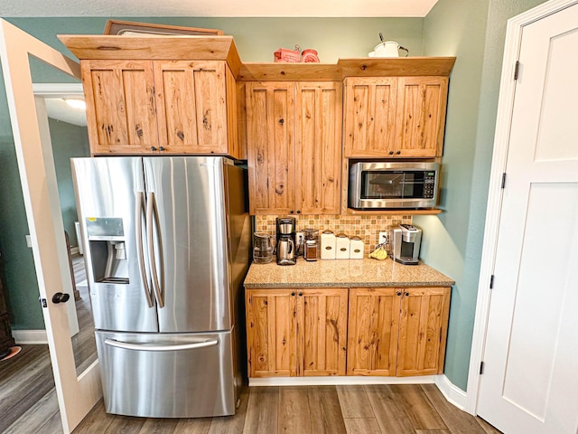 kitchen featuring light stone counters, tasteful backsplash, stainless steel appliances, baseboards, and wood finished floors