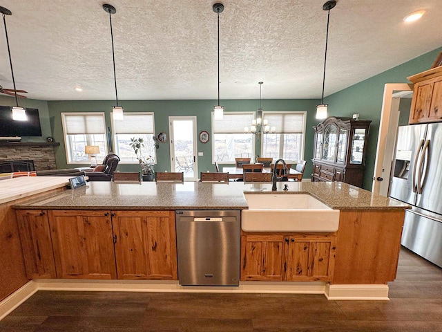kitchen featuring a sink, stainless steel appliances, dark wood-type flooring, a textured ceiling, and open floor plan