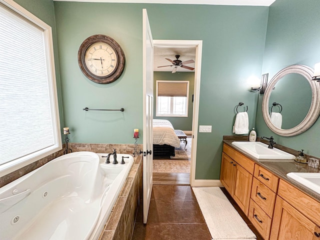 bathroom featuring a tub with jets, connected bathroom, double vanity, a sink, and a ceiling fan