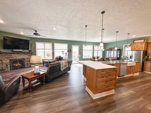 kitchen featuring a ceiling fan, open floor plan, a textured ceiling, and a large island with sink