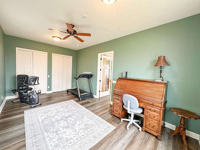 office space with a ceiling fan, wood finished floors, and baseboards