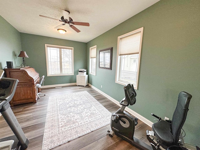 office space with baseboards, wood finished floors, and ceiling fan