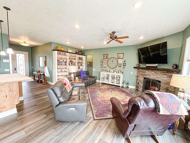 living room with a textured ceiling, baseboards, recessed lighting, wood finished floors, and a ceiling fan